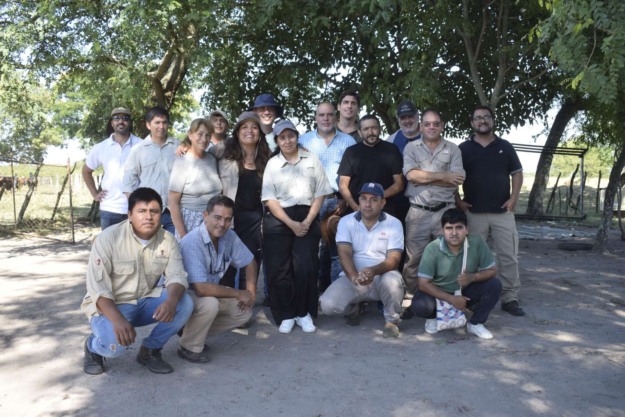 Un grupo de hombres y mujeres, integrantes del equipo técnico y la delegación internacional, posando juntos bajo la sombra de los árboles durante la visita de campo en Argentina.