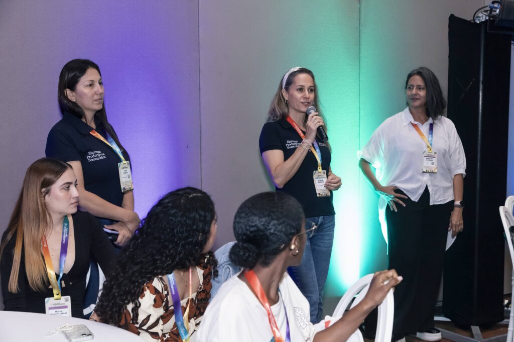 Tres mujeres líderes e investigadoras exponen con un micrófono durante un panel de discusión sobre sistemas productivos sostenibles en el evento de la comunidad Regeneradores.